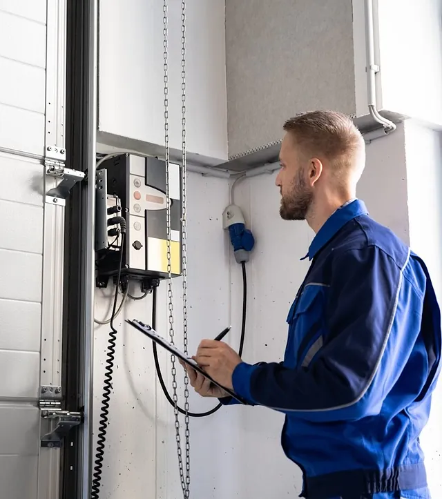 Mitarbeiter im blauen Overall von MKN Torservice Bremen führt eine Industrietor Reparatur durch.